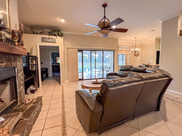 tiled living room featuring ornamental molding, ceiling fan with notable chandelier, and a stone fireplace