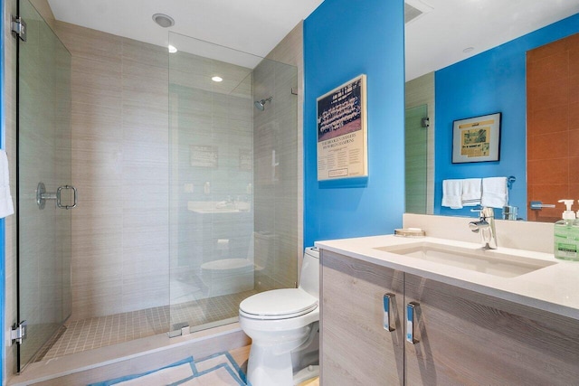 bathroom featuring a shower with shower door, toilet, and vanity