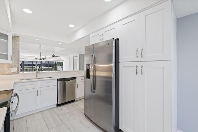 kitchen featuring white cabinets, appliances with stainless steel finishes, sink, tasteful backsplash, and light hardwood / wood-style floors