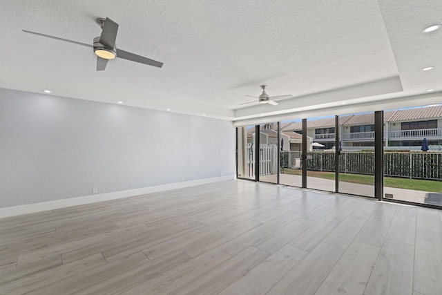 empty room with floor to ceiling windows, ceiling fan, and a textured ceiling