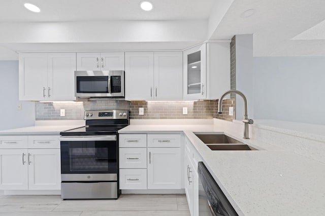 kitchen with appliances with stainless steel finishes, sink, backsplash, and white cabinetry