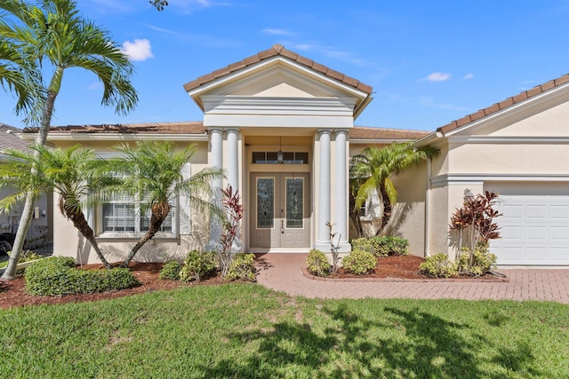 view of front of home featuring a garage, a tiled roof, french doors, and stucco siding