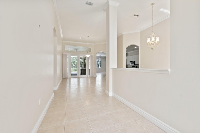 hall featuring light tile patterned floors, visible vents, arched walkways, and crown molding