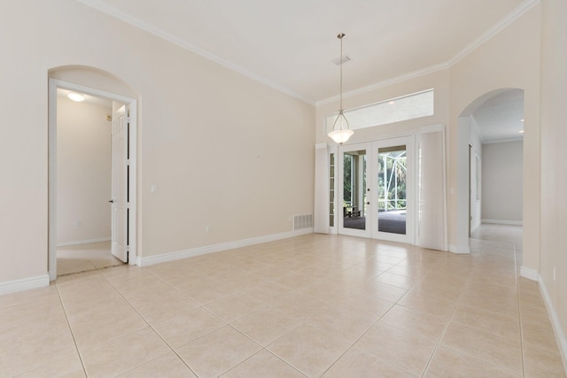 empty room with baseboards, visible vents, arched walkways, crown molding, and light tile patterned flooring