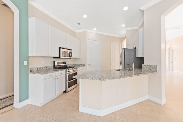 kitchen with appliances with stainless steel finishes, arched walkways, white cabinetry, and a peninsula