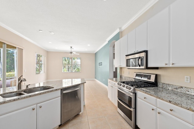 kitchen featuring stainless steel appliances, crown molding, a sink, and light tile patterned floors