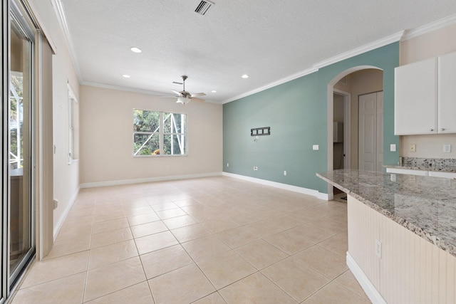 unfurnished living room with arched walkways, light tile patterned floors, and ornamental molding