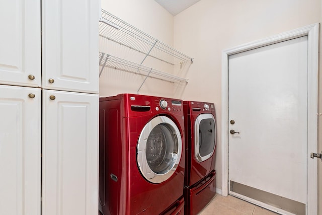 laundry area with cabinet space, washer and clothes dryer, baseboards, and light tile patterned floors