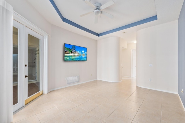 empty room with light tile patterned floors, visible vents, baseboards, french doors, and a raised ceiling