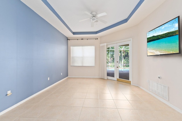 spare room featuring a tray ceiling, french doors, visible vents, light tile patterned flooring, and baseboards