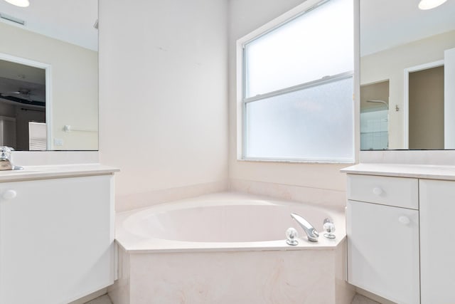 full bathroom with visible vents, vanity, and a bath