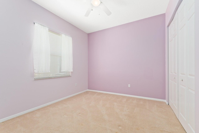 unfurnished bedroom featuring baseboards, ceiling fan, a closet, and light colored carpet