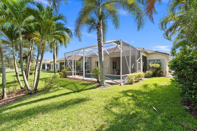 back of property with an outdoor pool, a lanai, and a yard