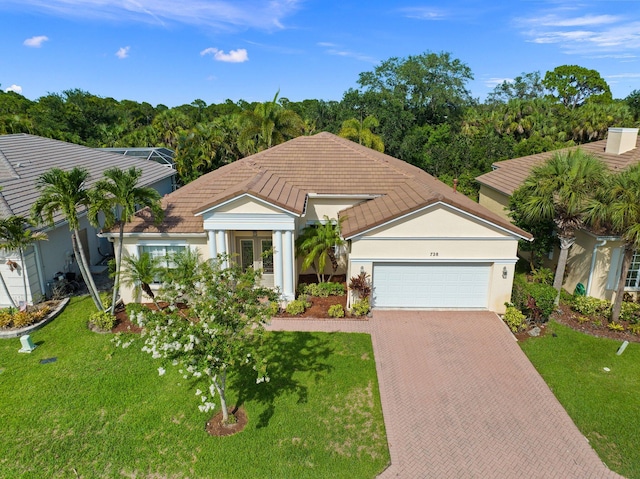 view of front of property with decorative driveway, an attached garage, a front lawn, and stucco siding