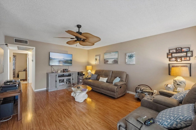 living room featuring a textured ceiling, ceiling fan, and light wood-type flooring