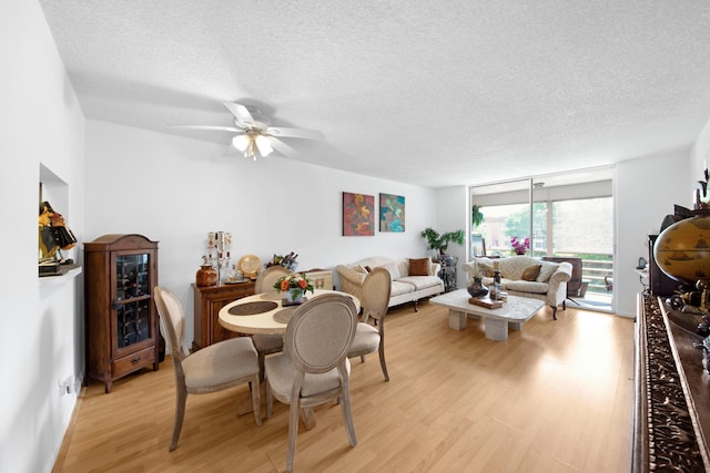 dining room featuring expansive windows, ceiling fan, light wood finished floors, and a textured ceiling