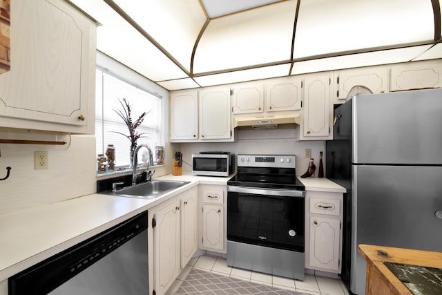 kitchen featuring light tile patterned floors, light countertops, under cabinet range hood, stainless steel appliances, and a sink