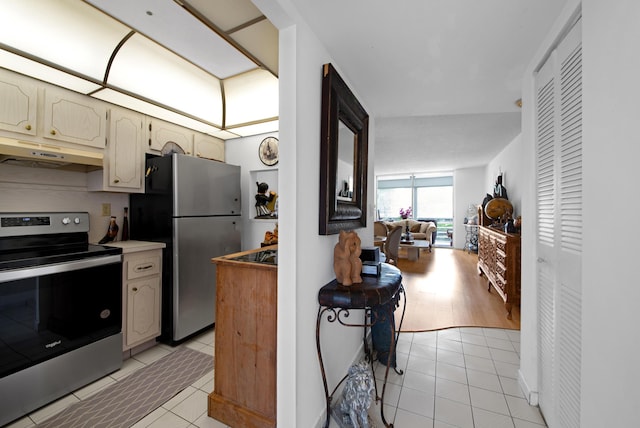 kitchen with light tile patterned floors, open floor plan, light countertops, under cabinet range hood, and appliances with stainless steel finishes
