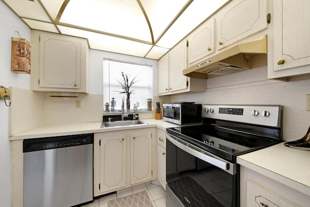 kitchen with light tile patterned floors, light countertops, under cabinet range hood, stainless steel appliances, and a sink