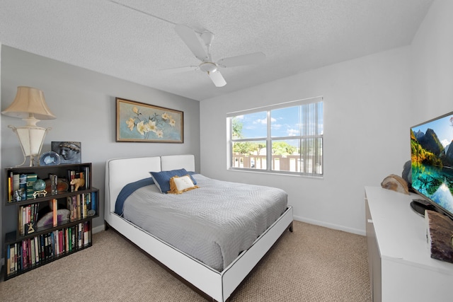 bedroom with baseboards, light colored carpet, a textured ceiling, and ceiling fan