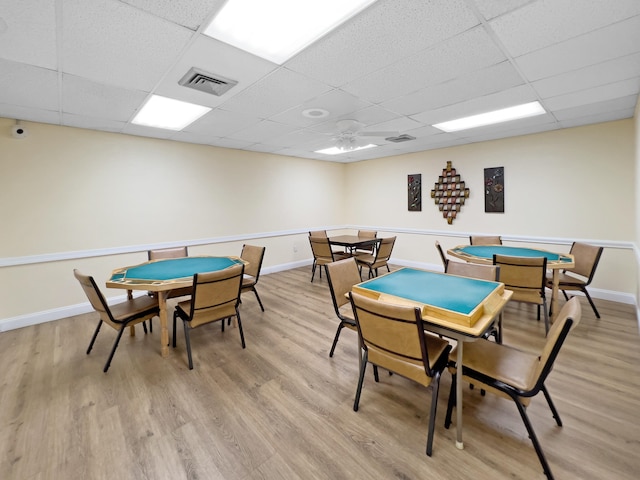 recreation room with light wood-type flooring, a paneled ceiling, and ceiling fan