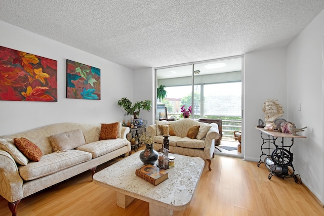 living room with light wood-style flooring, a textured ceiling, and floor to ceiling windows
