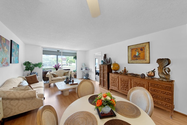 dining space featuring light wood-style flooring, a ceiling fan, and a textured ceiling