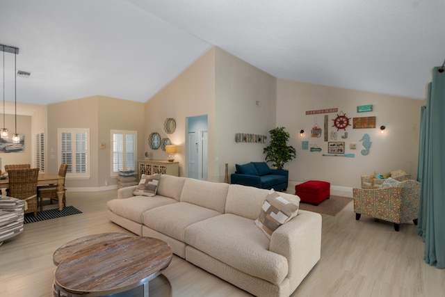 living room with light hardwood / wood-style floors and high vaulted ceiling