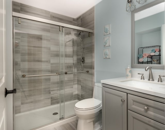 bathroom with oversized vanity, toilet, and a shower with shower door