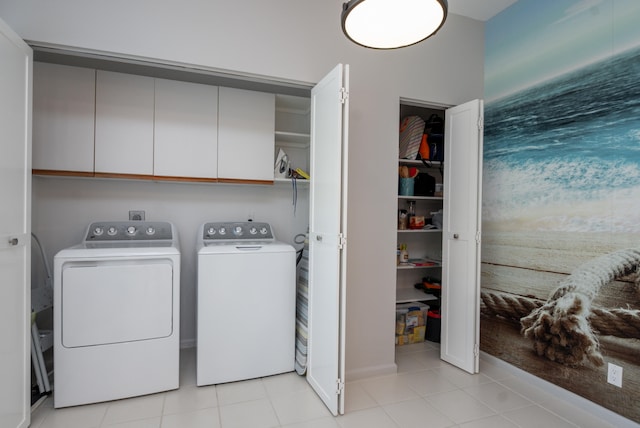 laundry room featuring electric dryer hookup, cabinets, light tile flooring, and washing machine and clothes dryer