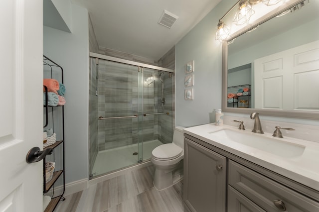 bathroom with a shower with door, large vanity, tile floors, and toilet