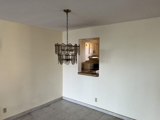 tiled spare room featuring a textured ceiling and an inviting chandelier