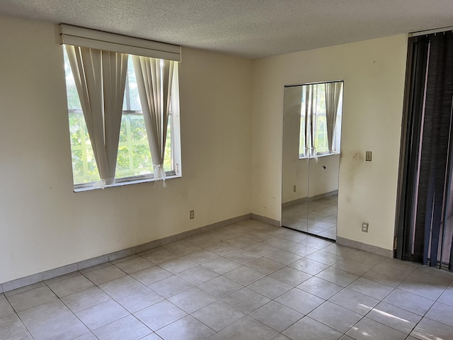 unfurnished room with light tile floors and a textured ceiling