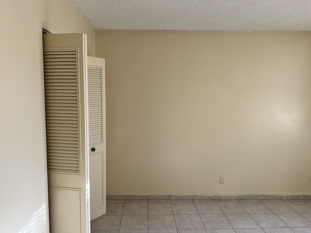 unfurnished room featuring light tile flooring and a textured ceiling