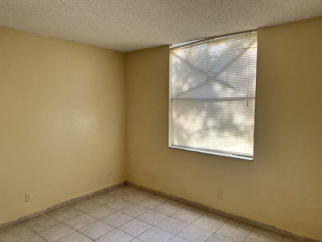 unfurnished room with light tile floors and a textured ceiling