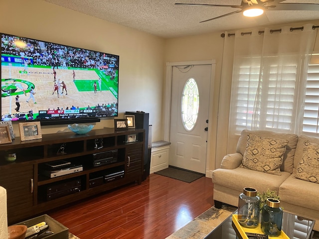 living room with dark hardwood / wood-style flooring, ceiling fan, and a textured ceiling