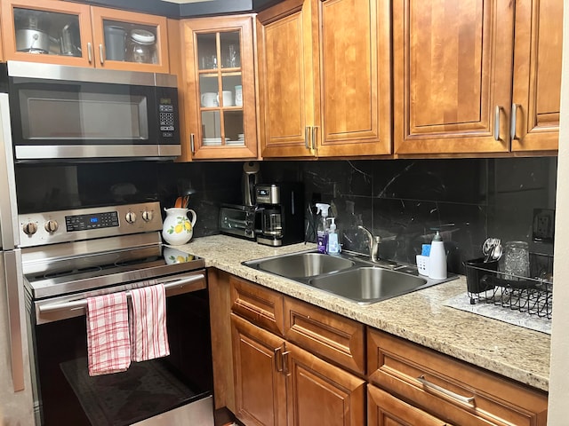 kitchen featuring sink, tasteful backsplash, stainless steel appliances, and light stone countertops