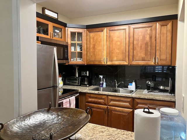 kitchen featuring backsplash, appliances with stainless steel finishes, sink, and light stone counters