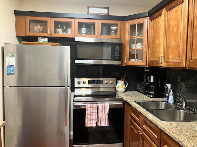 kitchen featuring light stone counters, tasteful backsplash, sink, and stainless steel appliances