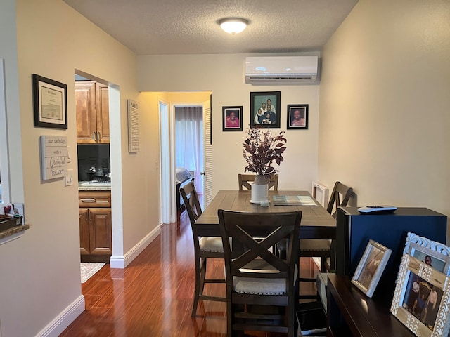 dining room featuring a textured ceiling, dark wood-type flooring, and a wall unit AC