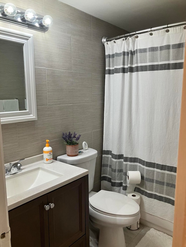 bathroom with tile walls, toilet, tile floors, and vanity