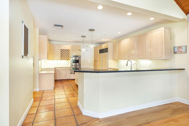 kitchen with paneled refrigerator, hanging light fixtures, light brown cabinetry, kitchen peninsula, and stainless steel double oven