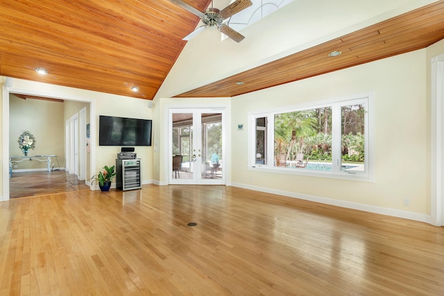 unfurnished living room with beverage cooler, french doors, light hardwood / wood-style flooring, a high ceiling, and ceiling fan