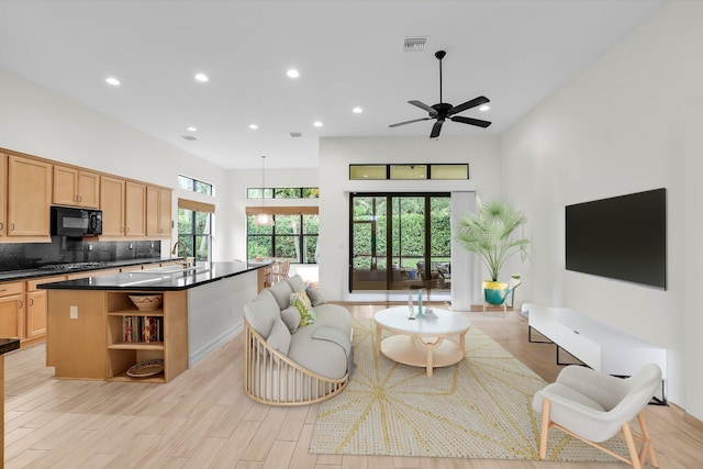 living room featuring light hardwood / wood-style flooring, ceiling fan, and sink