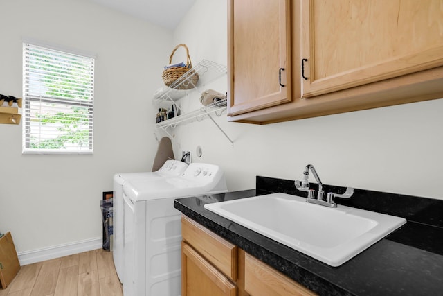 clothes washing area with cabinets, light hardwood / wood-style flooring, sink, and washing machine and clothes dryer