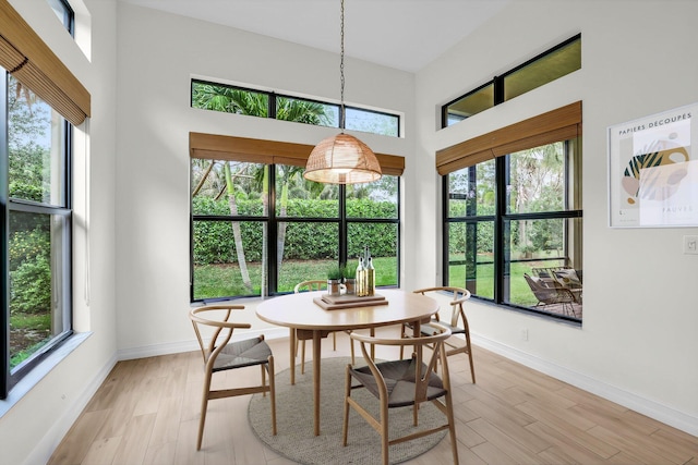 dining area featuring a wealth of natural light, a high ceiling, and light wood-type flooring