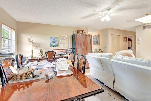 interior space featuring ceiling fan, light tile floors, and a textured ceiling