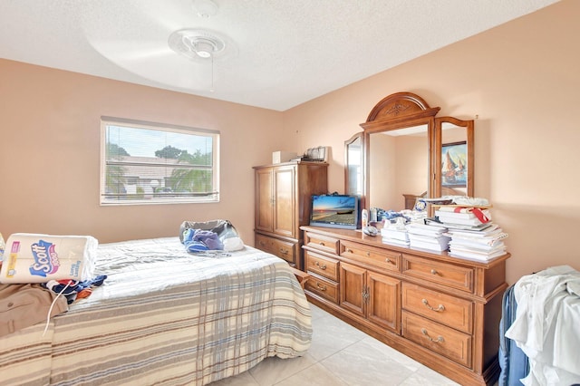 tiled bedroom with ceiling fan and a textured ceiling