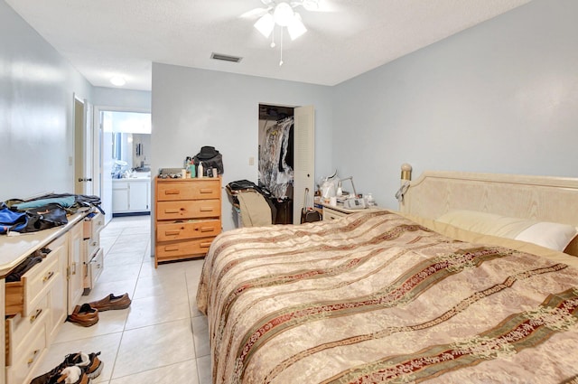 tiled bedroom featuring a closet, a textured ceiling, ceiling fan, and ensuite bathroom