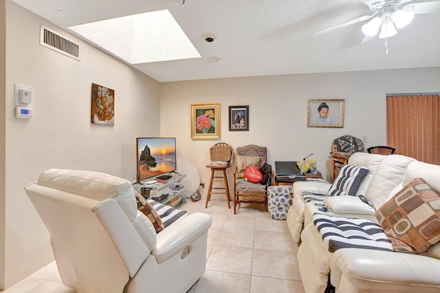 living room with a skylight, ceiling fan, and light tile flooring